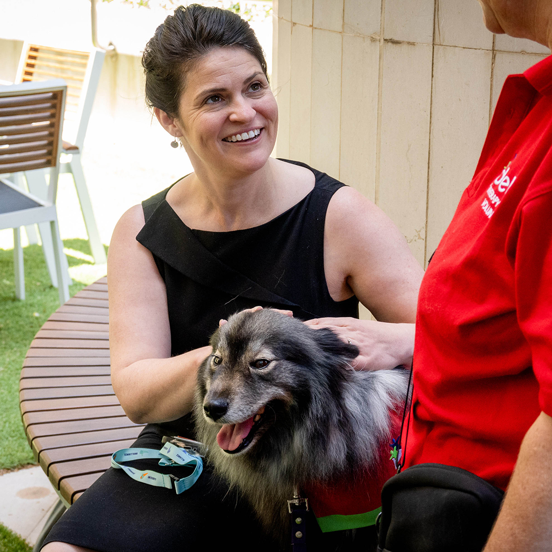 Smiling woman holding a dog by her side while its minder stand by